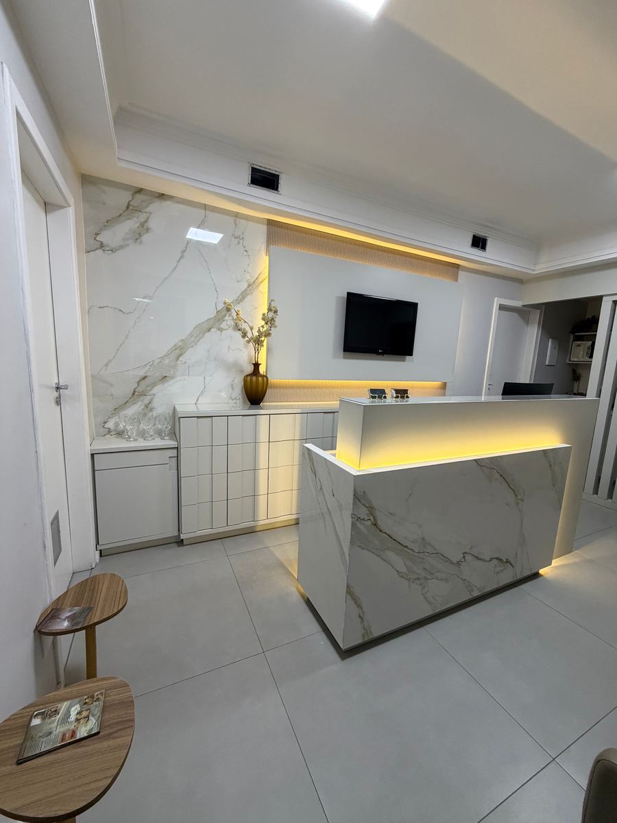 Recepção da DO Clinic com bancada de mármore e iluminação dourada